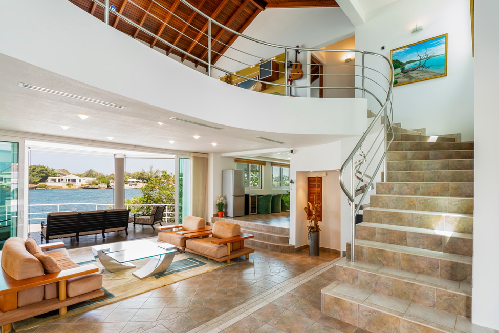 A sophisticated two-story foyer with accented curved staircase and a revealing view of the Spanish water bay.