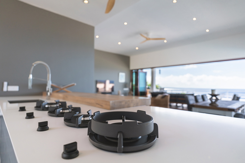 An integrated cooktop counter sits on this eat-at kitchen with ocean views.